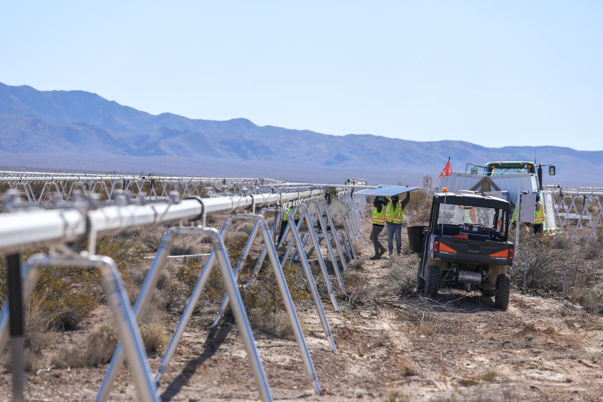 Construction workers carry photovoltaic panels for installation at the Gemini solar project in southern Nevada in 2023.