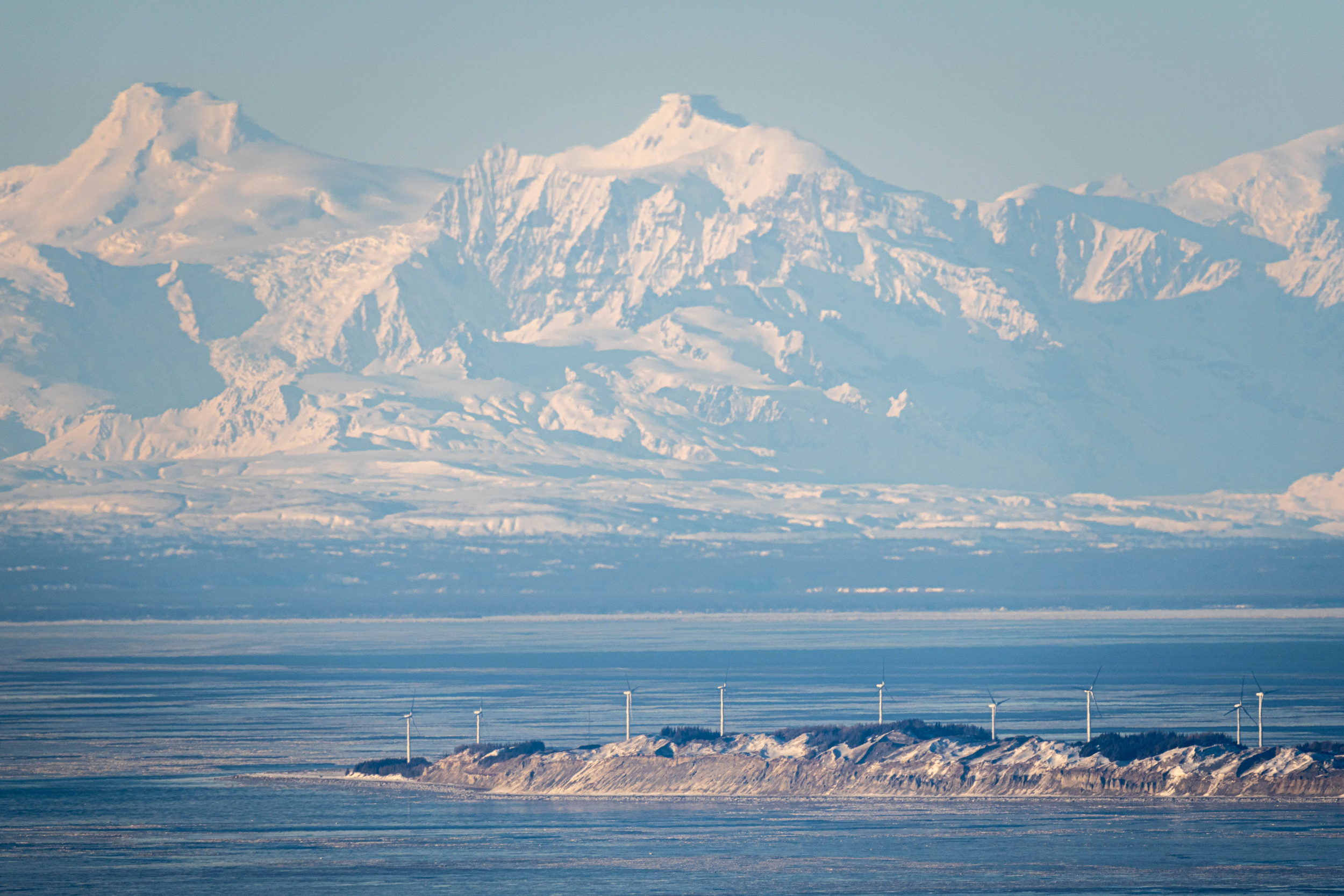 The Tordrillo mountains rise behind wind turbines on Fire Island. Currently, this small wind farm is the only one generating electricity for Chugach Electric Association, which provides power to the Anchorage area. Credit: Loren Holmes/ADN