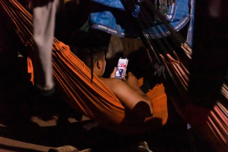 Someone in a hammock in the dark looking at a mobile phone