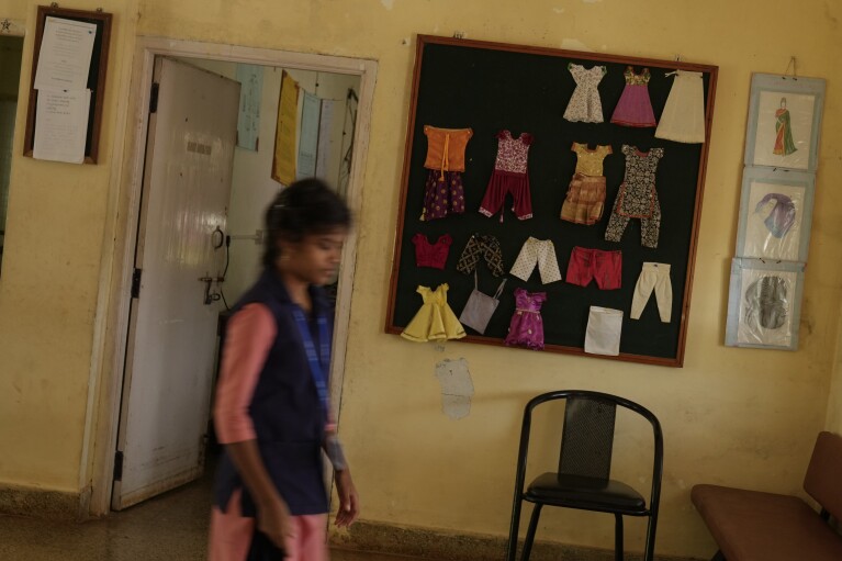 A student enrolled for a professional training course walks past a display of clothes stitched by tailors who use electric sewing machines to make clothes, at the campus of the Swami Vivekananda Youth Movement, a nongovernmental organization that works to help poor and Indigenous communities, in Kenchanahalli, India, Monday, Sept. 23, 2024. (AP Photo/Aijaz Rahi)