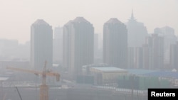 FILE - A construction site is seen against the backdrop of skyscrapers on a day with high air pollution in Beijing, China, March 11, 2021.