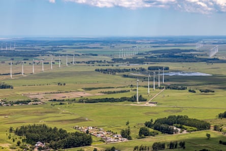 Aerial view of dozens of wind turbines on a verdant plain