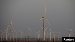 FILE - A car drives near wind turbines on a power station near Yumen, Gansu province, China, September 29, 2020.