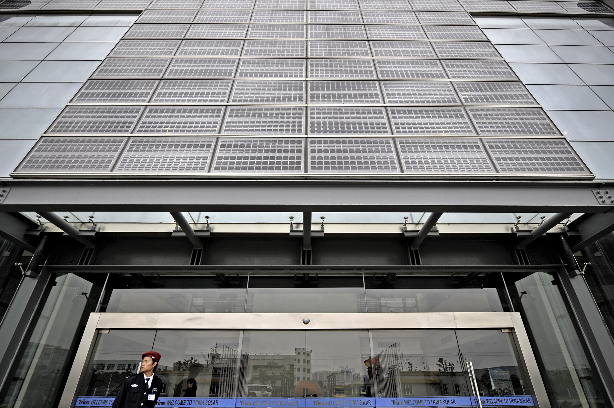 A security guard standing under solar panels at the entrance of solar cell maker Trina Solar in Changzhou, China.