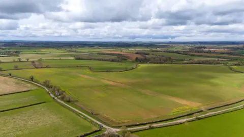 PA Media A drone shot of green fields in the area stretching into the distance with a couple of small lanes