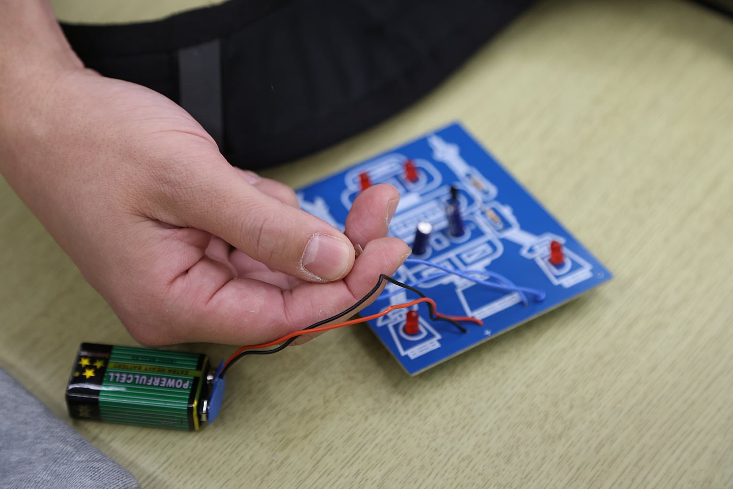 A student tested a circuit board after soldering the pieces into place during a digital principals lab class. When working, the red lightbulbs illuminate. 