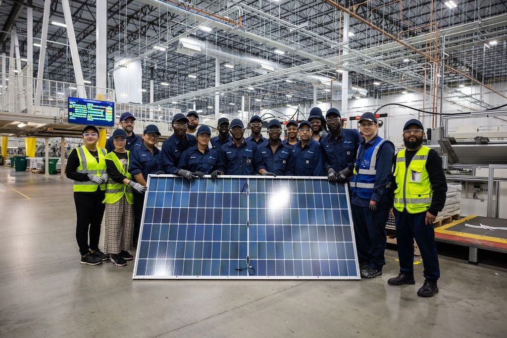 Workers stand behind a solar panel at the Illuminate USA factory in Pataskala, Ohio.