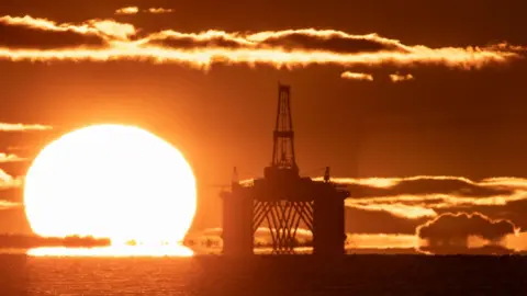 PA Media The sun rising behind a redundant oil platform moored in the Firth of Forth near Kirkcaldy, Fife